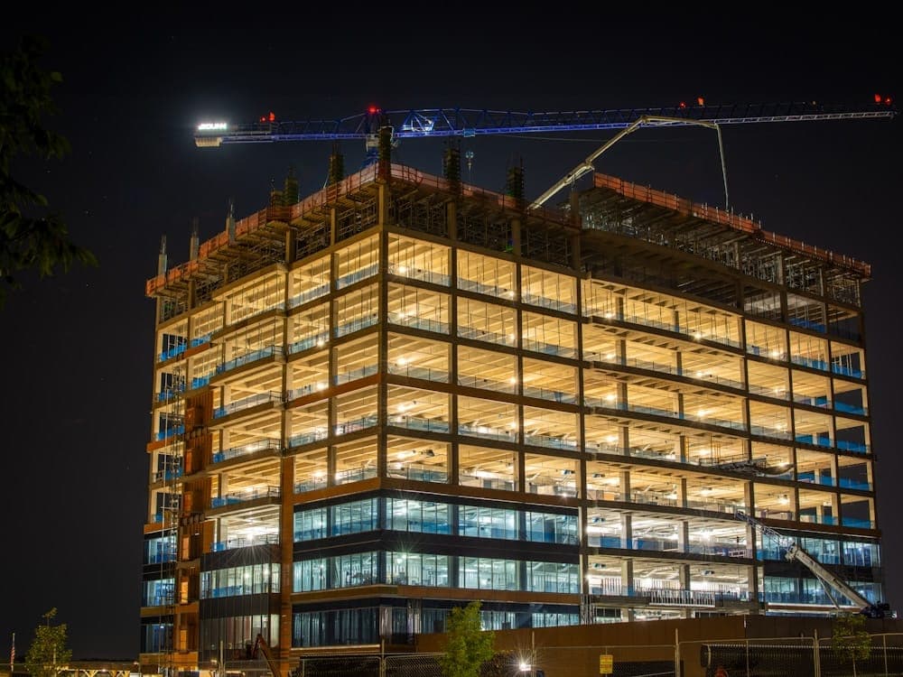 Edifício em construção iluminado à noite, com a grua ainda montada sobre a laje.